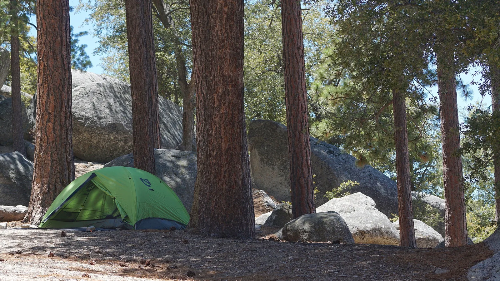 A single small tent pitched among ponderosa pines and granite boulders at Marion Mountain Campground in the San Bernardino National Forest.
