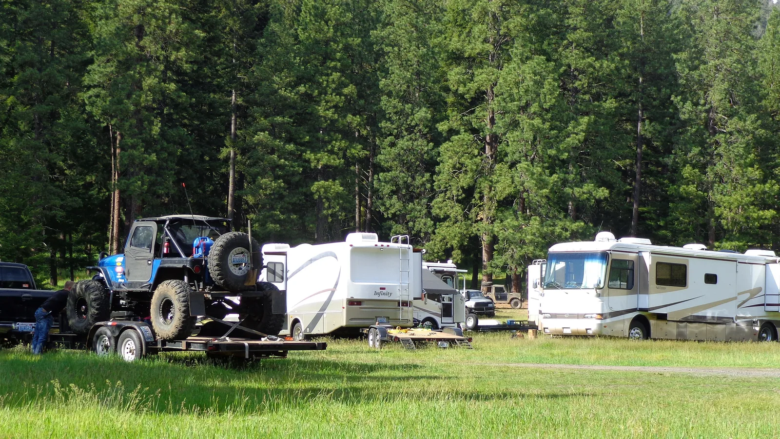 Three different kinds of rig parked side by side at a Bureau of Land Management recreation site — a Class A motorhome, a fifth wheel and a travel trailer.